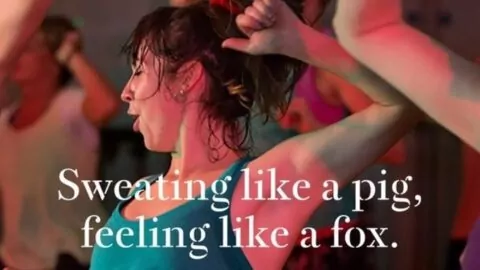 A woman participates in an exercise class, sweating profusely. She's wearing a teal tank top. Overlaid text reads: 