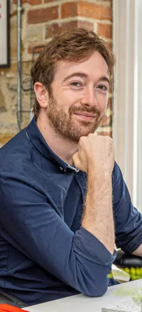Dr. Nathan Hunt looking at the camera and smiling while resting his head on his hand