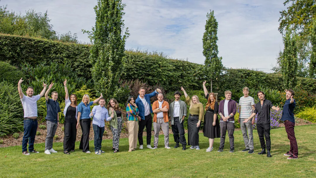 The Fishtank Agency team stood on a lawn with a hedge in the background and a cloudy sky.