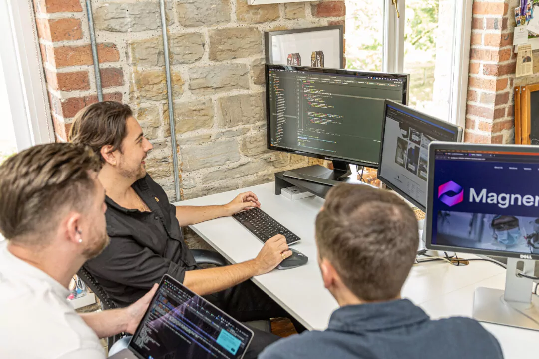 Three members of the Fishtank web development team sitting around computers and chatting.