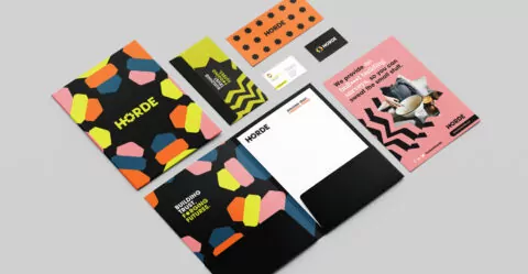 Horde stationary including a folder, letterhead and business cards. They are all brightly patterned with abstract shapes.