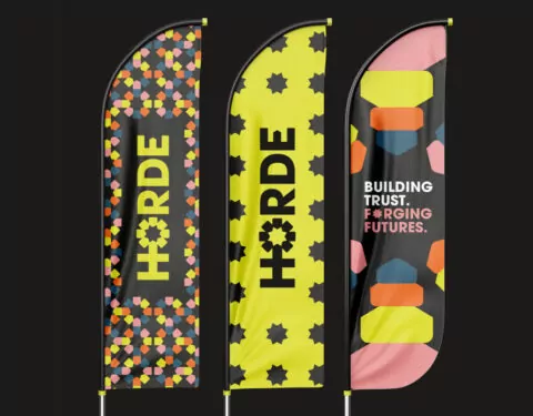 Three flags on a black back ground showing 'Horde' logos and messaging. The flags are various brightly coloured patterns.