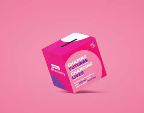 A pink donation box floats against a pink background. It says, 